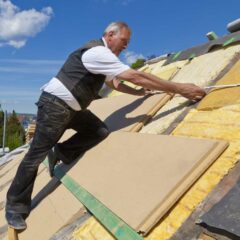 Dachdecker legt Dämmmaterial auf das Dach eines Hauses.